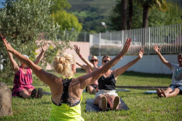 Un grupo de personas sentadas sobre esterillas de yoga al aire libre.