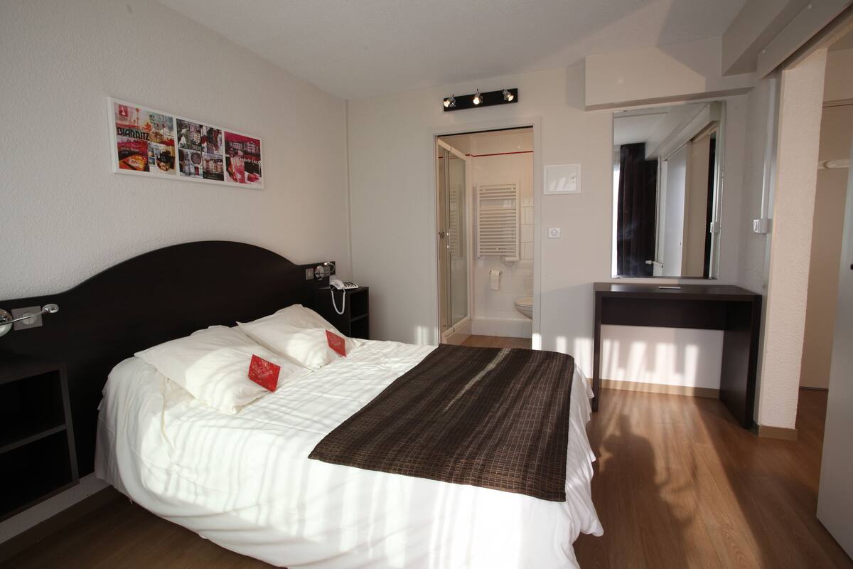 A bedroom with a bed, bedside table, and a desk.
