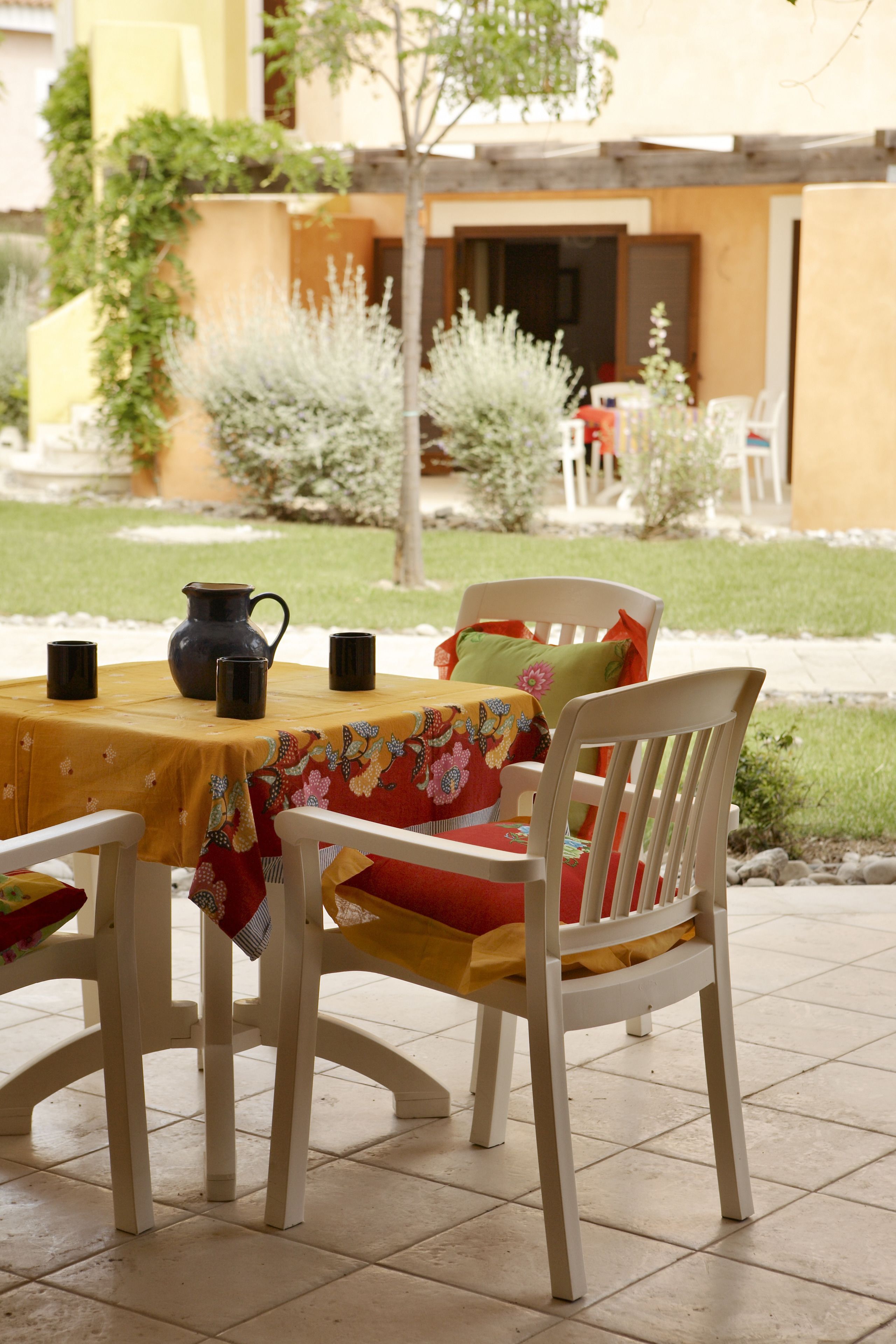 Une terrasse avec une table dressée pour deux personnes, une carafe et deux mugs.