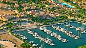 An aerial view of a marina with numerous boats docked, surrounded by residential buildings and greenery. - Agave Apartments (Pisticci)