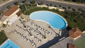 An aerial view of a resort with a large swimming pool, sun loungers, and a small building. - Agave Apartments (Pisticci)