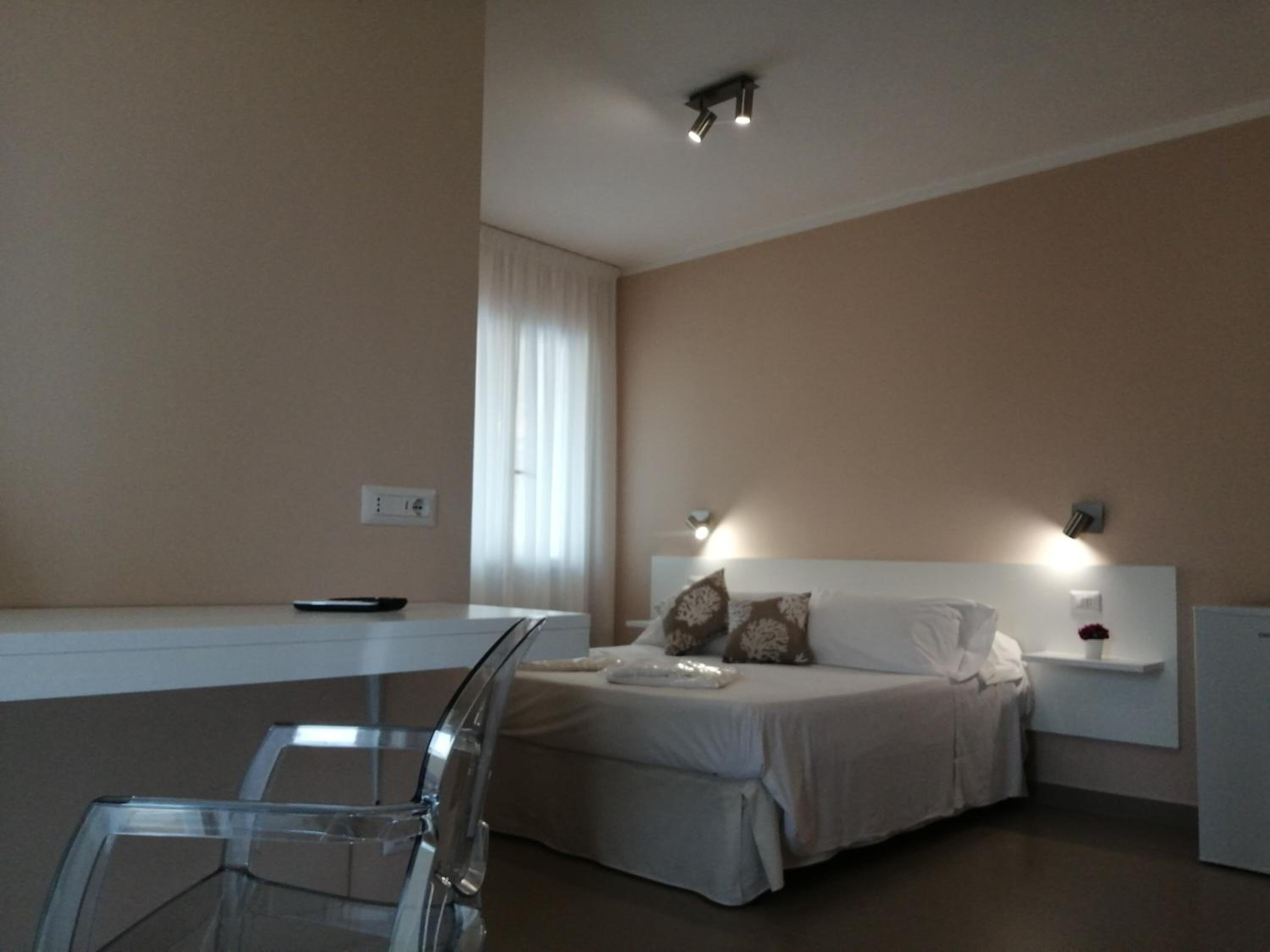 A modern bedroom with a bed, bedside tables, and a glass table.