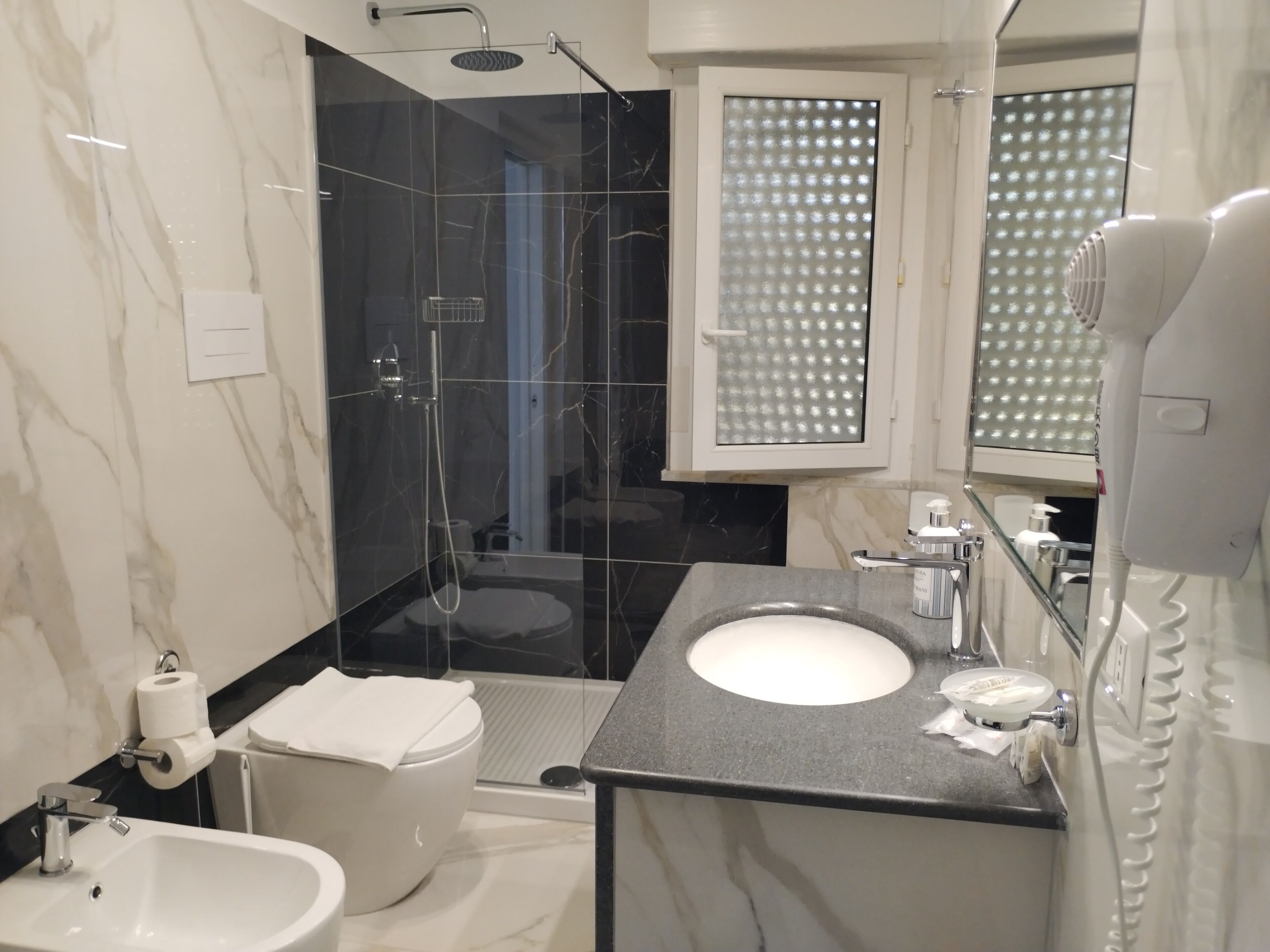 A modern bathroom with a glass-enclosed shower, a white toilet, a sink, and a mirror.