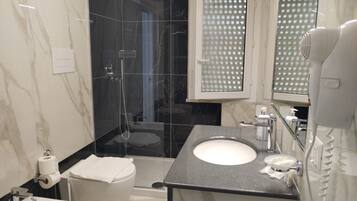 A modern bathroom with a glass-enclosed shower, a white toilet, a sink, and a mirror.