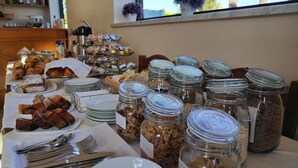 A buffet table with various food items, including pastries, cereals, and condiments, arranged on plates and in jars. - Residence Hotel Villa Laura (Ascea)