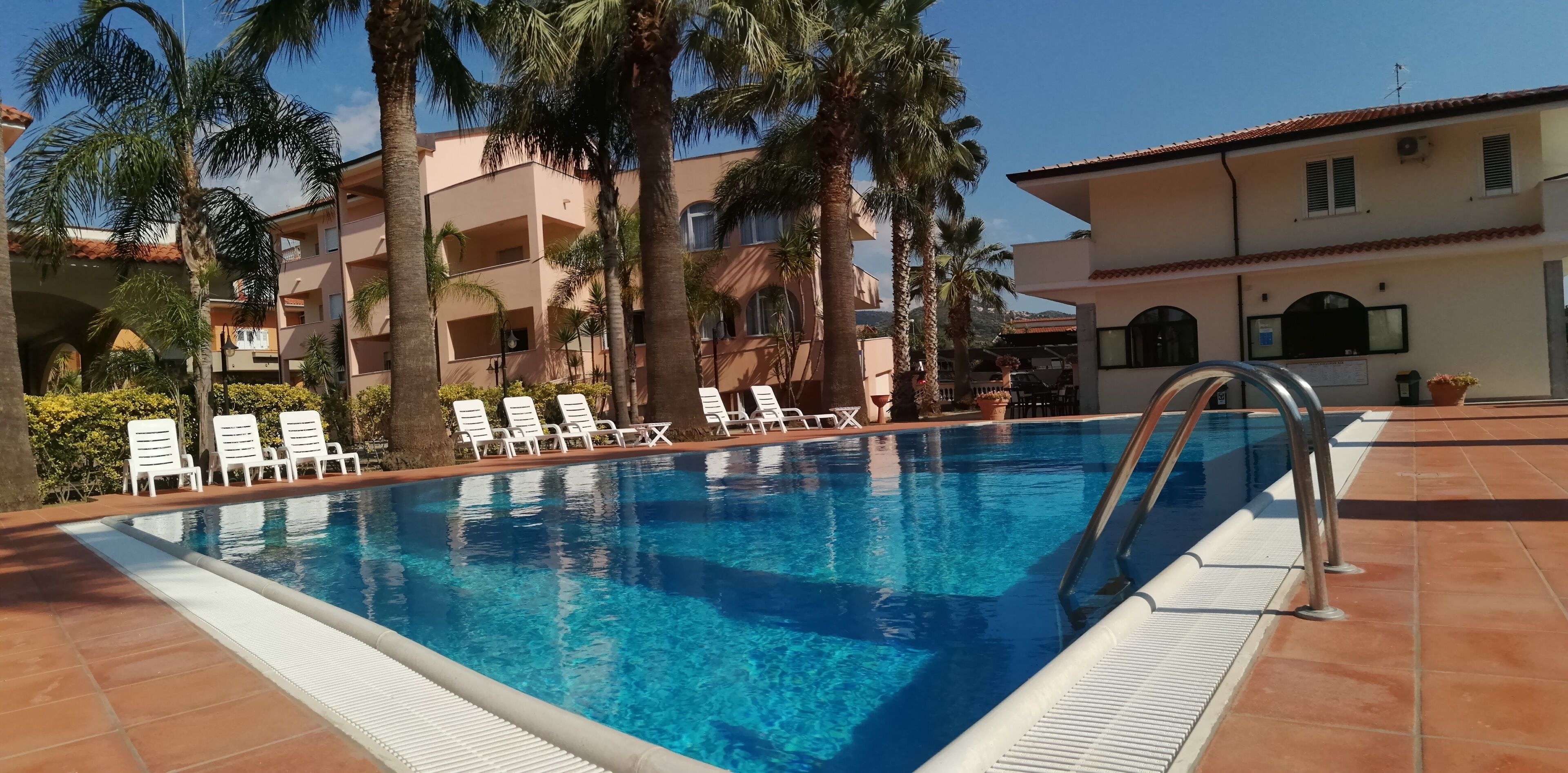 Una piscina con poltrone da sdraio bianche e palme.