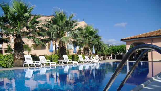 A swimming pool with white lounge chairs and palm trees. - Residence Hotel Villa Laura (Ascea)