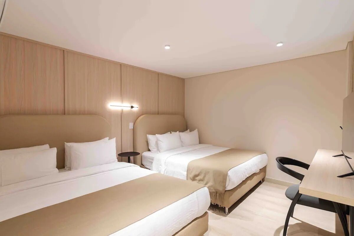 Habitación de hotel con dos camas, un escritorio y una silla.