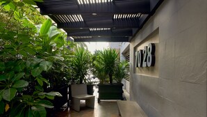 A modern outdoor seating area with planters and a number sign on the wall. - Hotel Lincoln (Medellín)