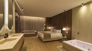 A modern bedroom with a large bed, a separate sofa, a bathtub, and a vanity with a mirror. - Hotel Lincoln (Medellín)