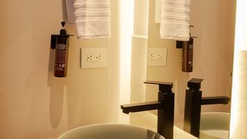 A bathroom with a round sink, two towel racks, and a mirror.