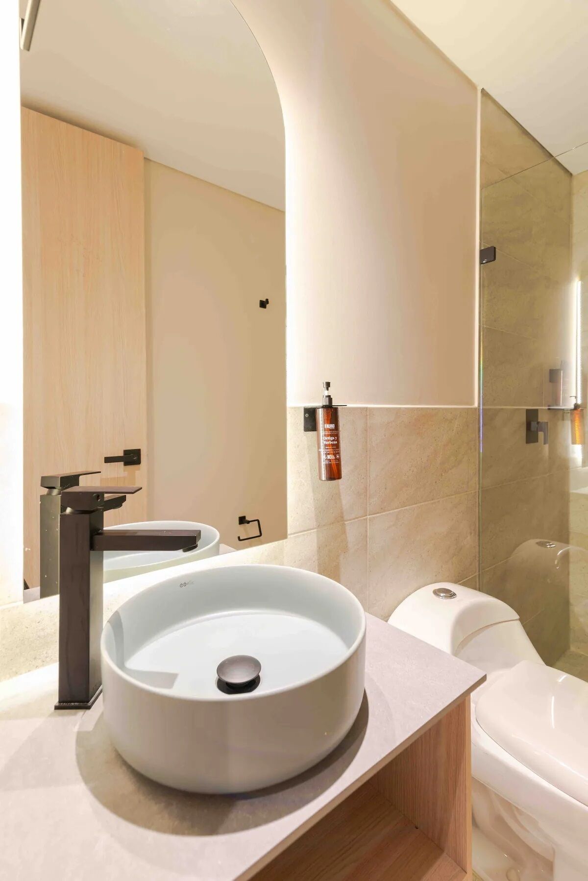 Een moderne badkamer met een grote ronde wasbak, een toilet en een douchehoek.