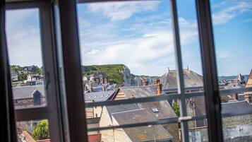 A view through a window of a town with buildings, a hill, and a clear sky.