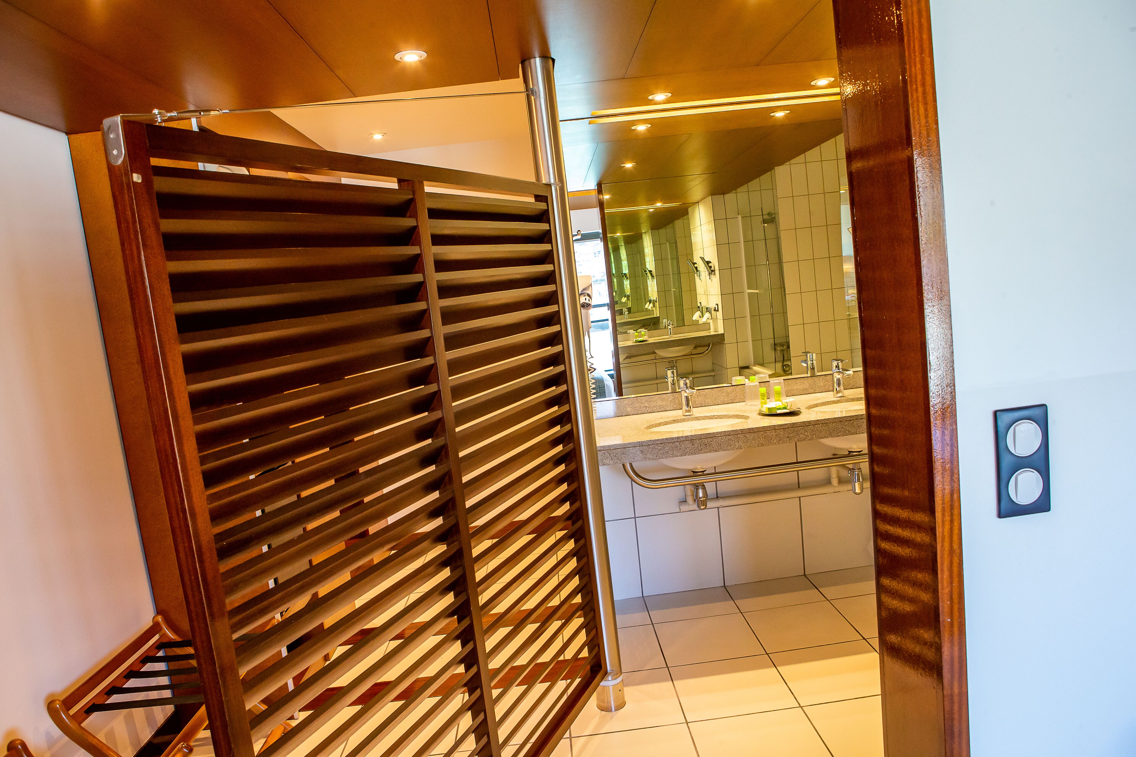 A modern bathroom with a glass shower enclosure, a sink with a mirror, and a towel rack.