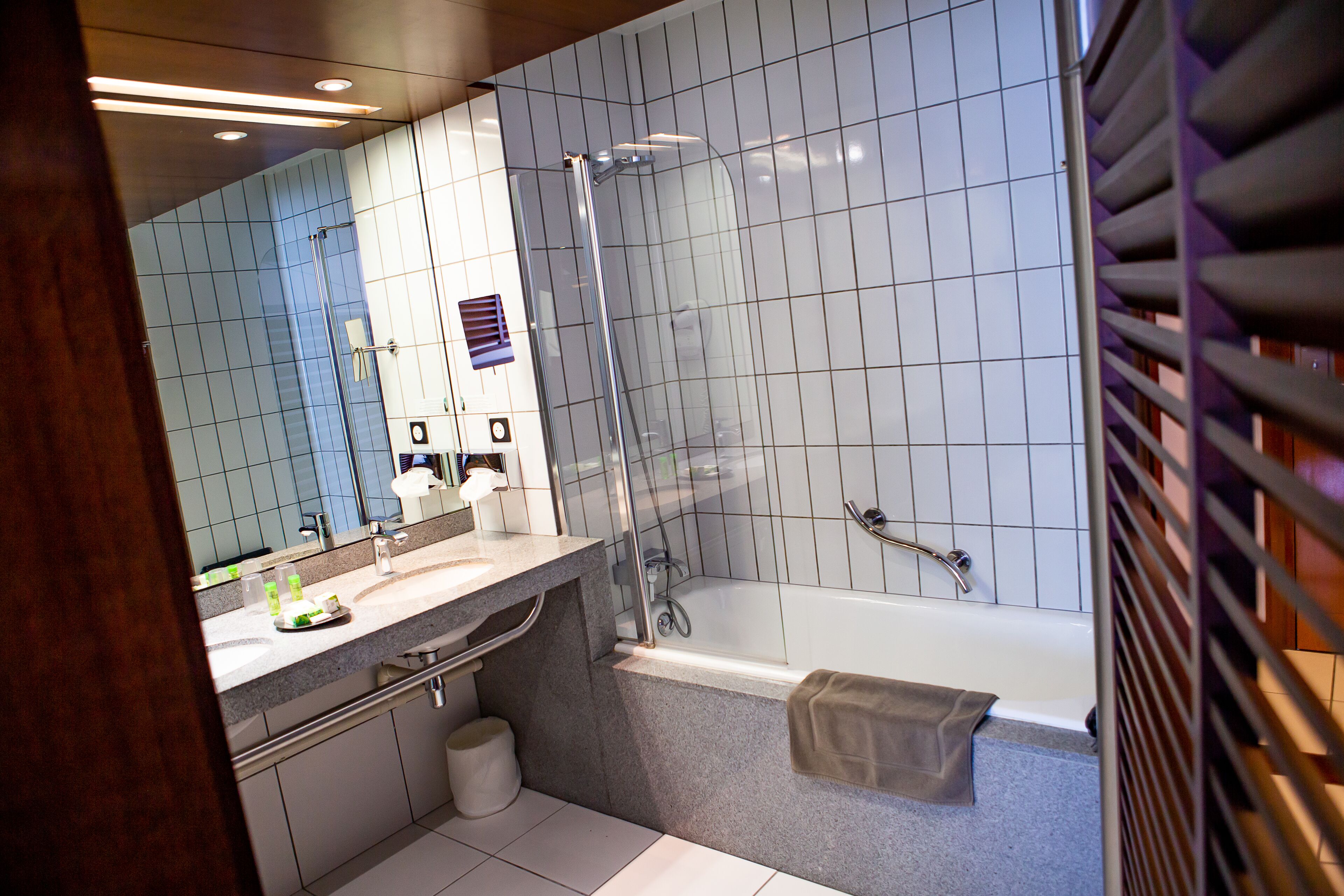 A modern bathroom with a glass-enclosed shower, a bathtub, and a vanity with a mirror.