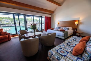 A hotel room with a bed, seating area, and a view of a harbor. - Le Grand Pavois (Fecamp)