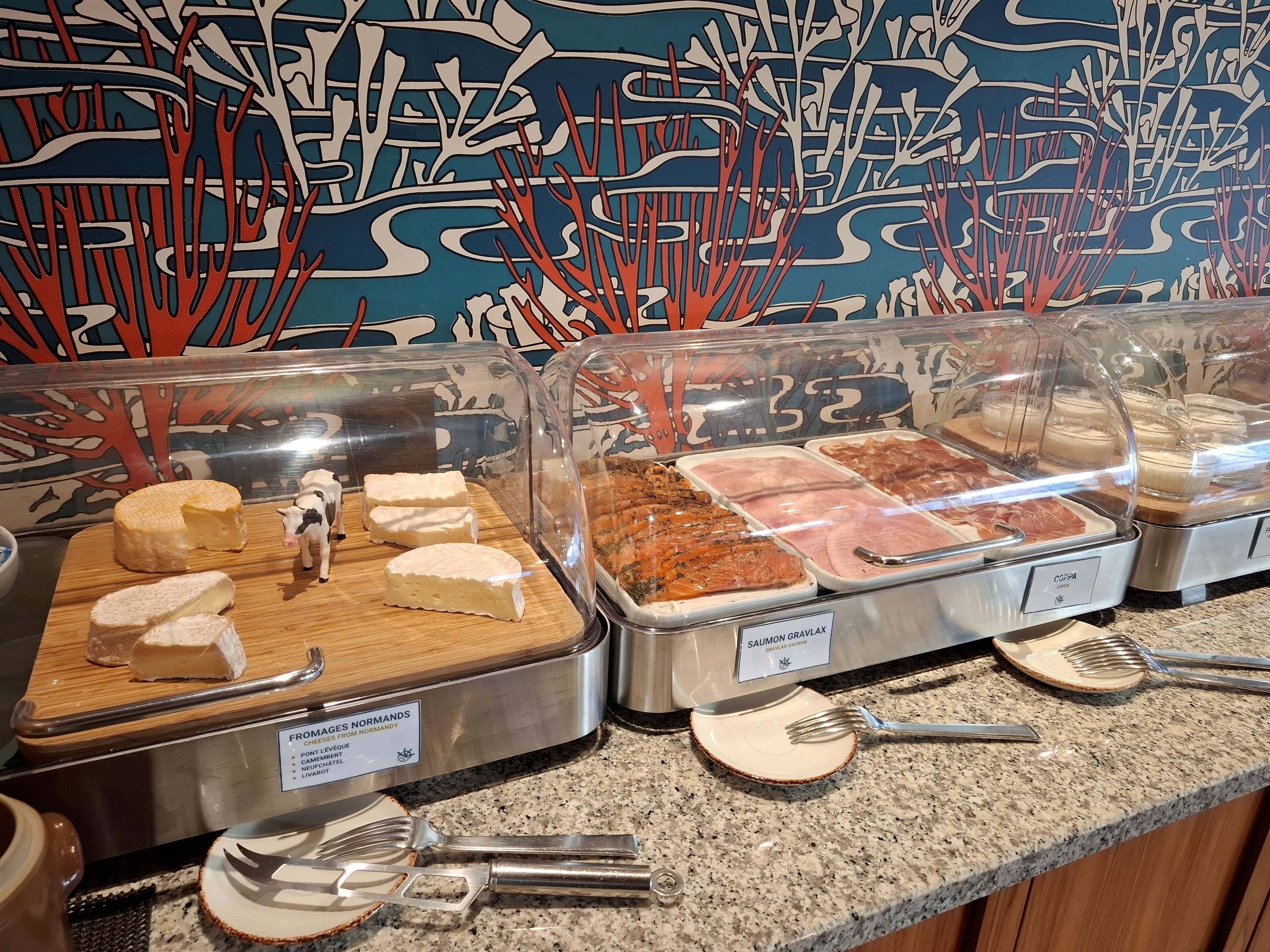 A buffet with various food items, including cheese, meats, and seafood, displayed in clear containers.