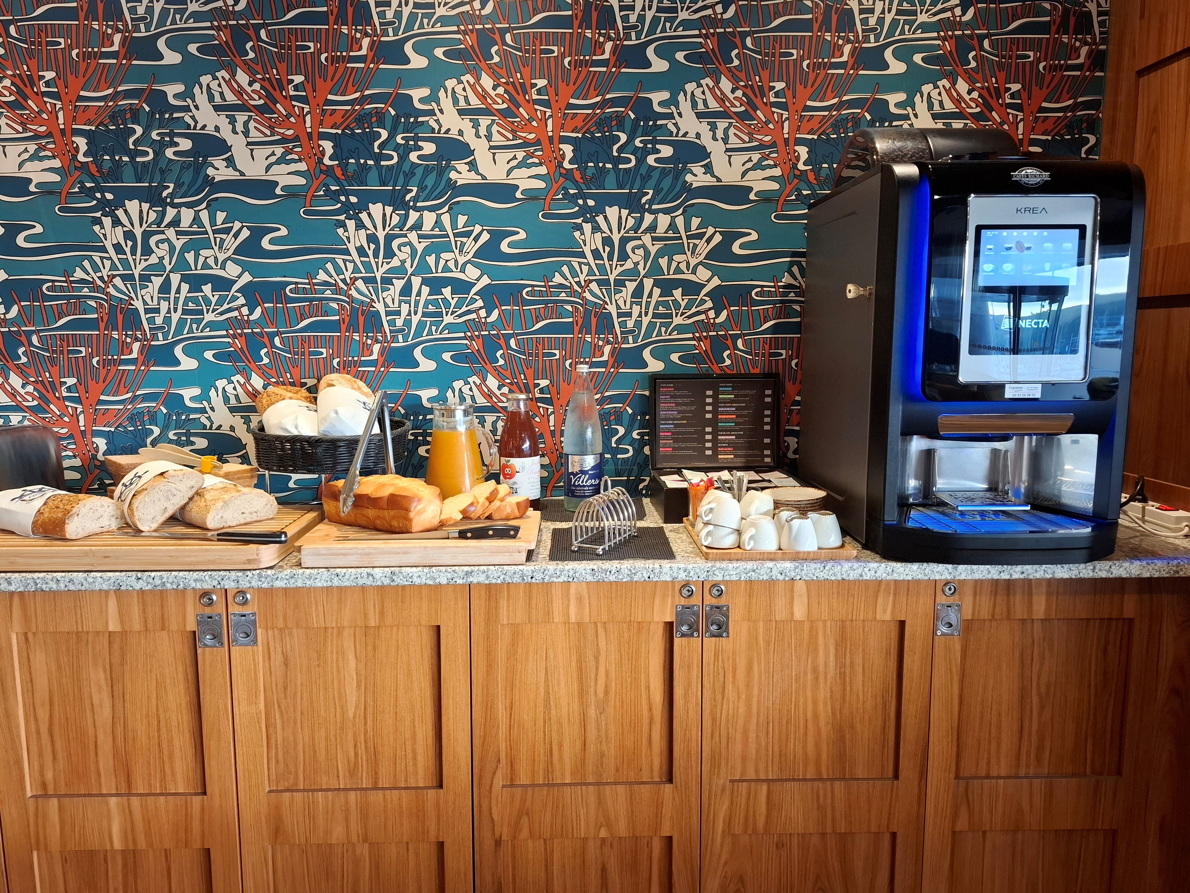 Una barra de desayuno con pan, jugo y una máquina de café.