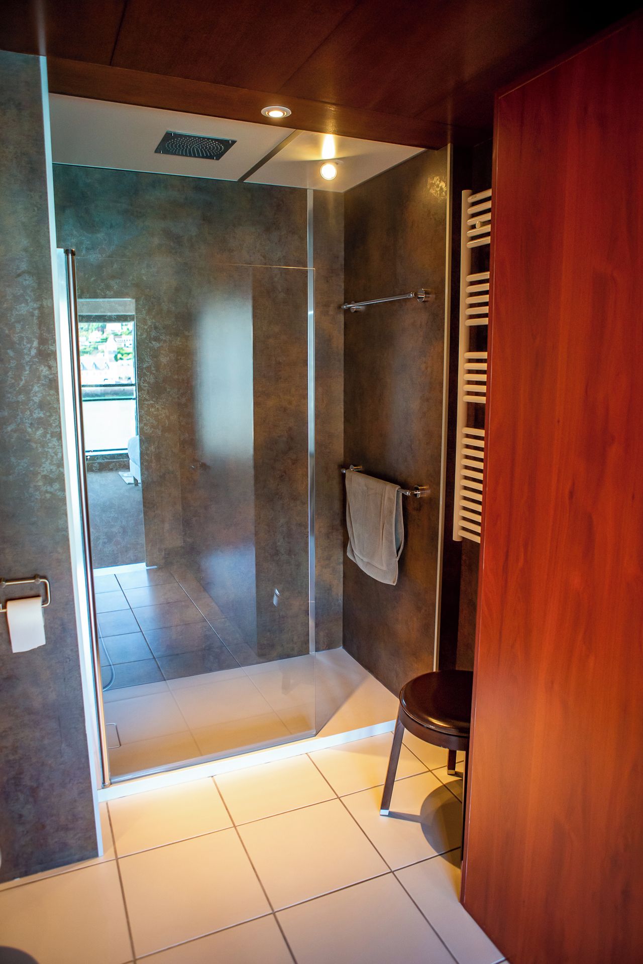 Un baño moderno con cabina de ducha de vidrio, un perchero para toallas y un tocador de madera.