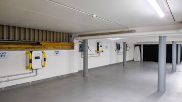 A spacious parking garage with concrete floors and walls, featuring parking meters and signs indicating parking places.