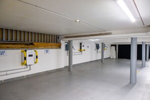 A spacious parking garage with concrete floors and walls, featuring parking meters and signs indicating parking places. - Le Grand Pavois (Fecamp)