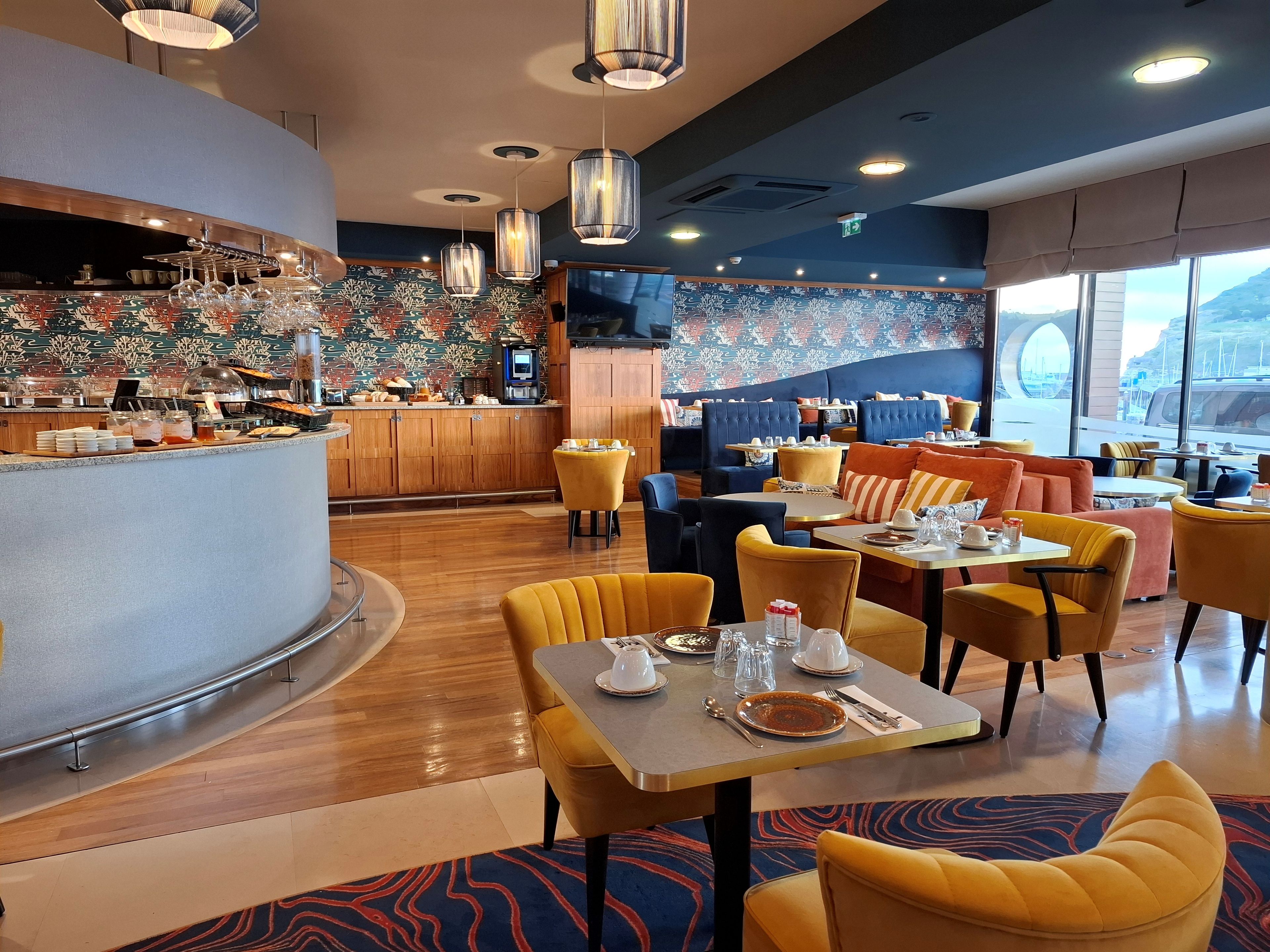 Un restaurante con mostrador, zona de estar y vistas al exterior.