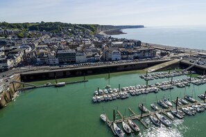 A coastal town with a marina filled with boats, a promenade, and buildings along the waterfront. - Le Grand Pavois (Fecamp)