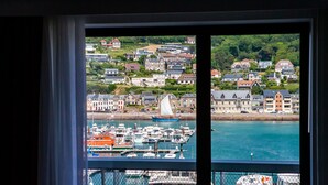 A view of a marina with boats docked, a sailboat, and a town with houses in the background. - Le Grand Pavois (Fecamp)