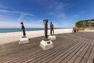 Un paseo marítimo de madera con tres estatuas de bronce.