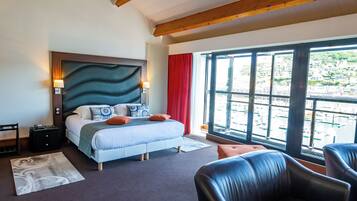 A hotel room with a bed, a desk, a chair, and a large window with a view of a marina.
