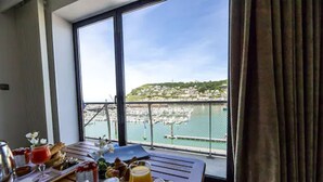 A balcony with breakfast setup overlooking a marina and a hilly town. - Le Grand Pavois (Fecamp)