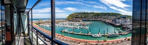 A marina with boats docked, a pier, and a hill with buildings in the background. - Le Grand Pavois (Fecamp)