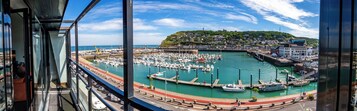 Una marina con barcos amarrados, un muelle y una colina con edificios al fondo.