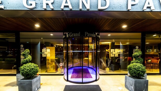 The entrance to Le Grand Pavoi with a revolving door, two potted plants, and a glass facade. - Le Grand Pavois (Fecamp)