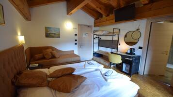Une chambre à coucher comprenant un lit, un canapé, un bureau avec une chaise, un miroir et un téléviseur fixé au mur.