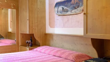 Una stanza in legno con un letto, un quadro raffigurante un paesaggio innevato e un armadio in legno.