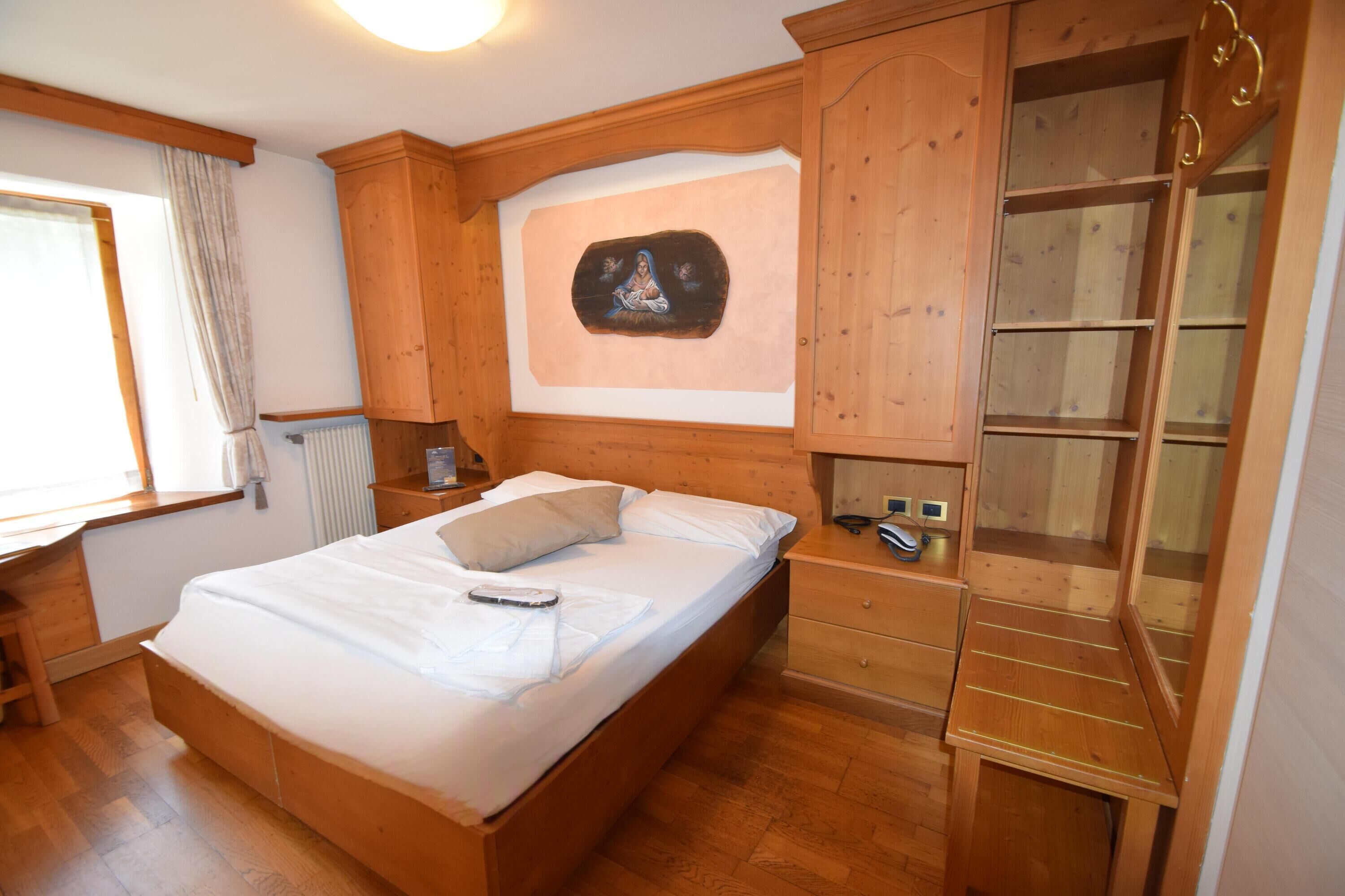 Dormitorio con estructura de madera, cama, mesita de noche y armario empotrado con puertas de vidrio.