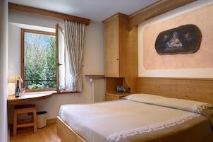 Un dormitorio con una cama de madera, un escritorio con lámpara, un radiador y un cuadro en la pared.