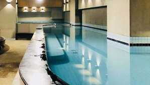 A long, empty swimming pool with a curved edge, surrounded by walls with recessed lighting. - Single inn kaohsiung Lisen Hostel (Kaohsiung)
