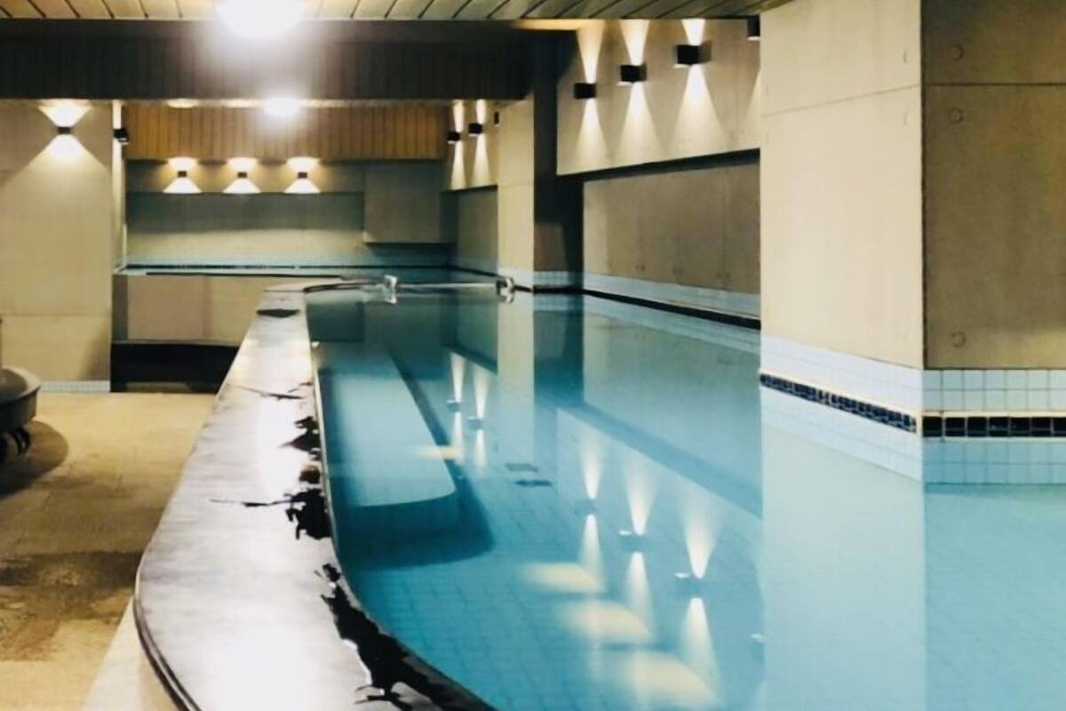 A long, empty swimming pool with a curved edge, surrounded by walls with recessed lighting.