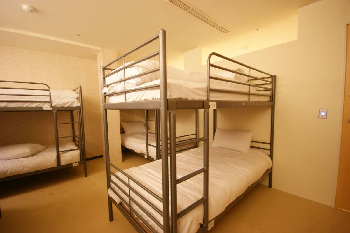 A room with bunk beds, a door, and a light switch on the wall.