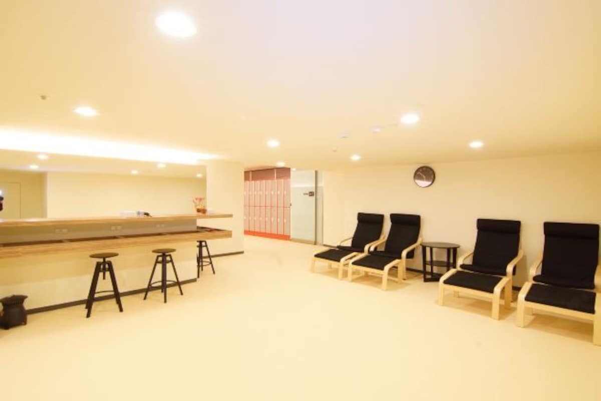 A reception area with a counter, bar stools, and lounge chairs.