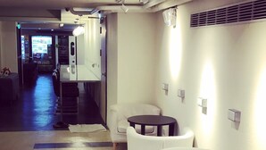 A modern hotel lobby with white leather sofas, a small round table, and a vending machine. - Single inn kaohsiung Lisen Hostel (Kaohsiung)