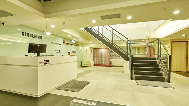 A hotel reception area with a reception desk, a staircase, and a sign indicating women's and men's restrooms. - Single inn kaohsiung Lisen Hostel (Kaohsiung)