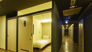 A hotel corridor with wooden flooring, a bed with a white mattress and pillow, and doors numbered 07 and 16-25. - Single inn kaohsiung Lisen Hostel (Kaohsiung)