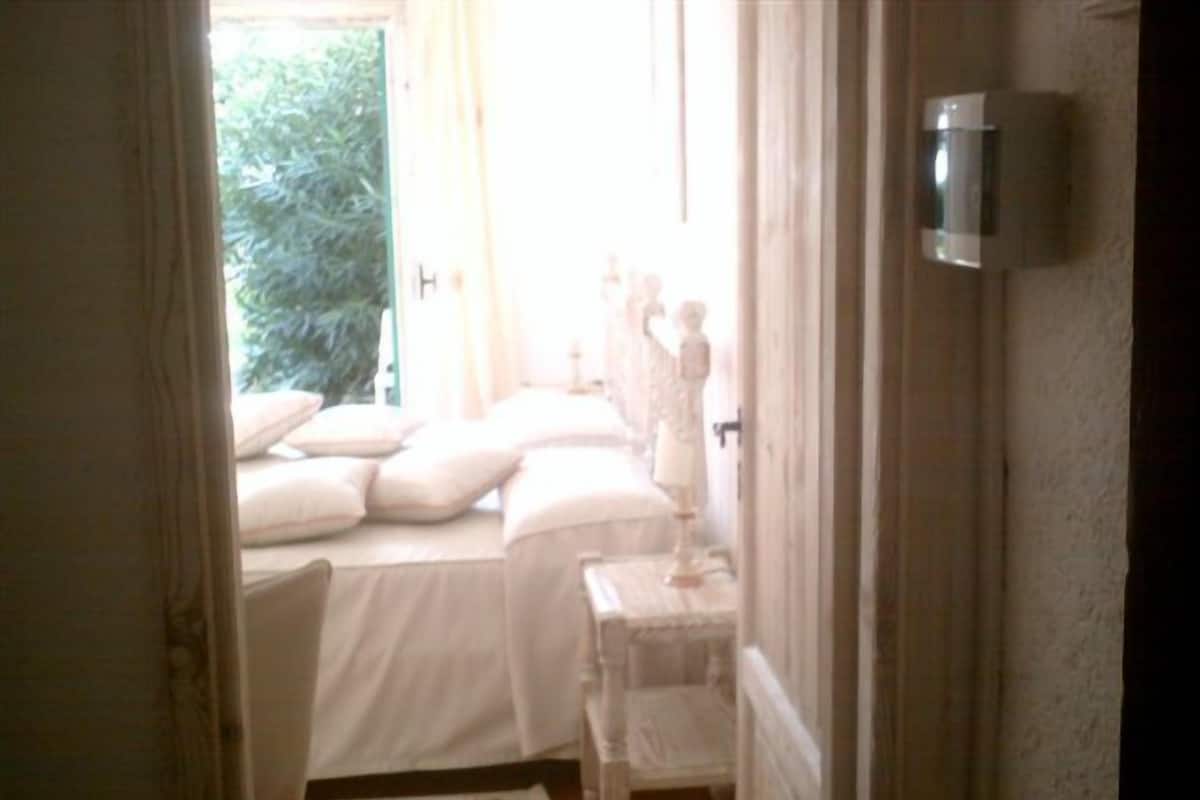 Une chambre à coucher avec un lit, des oreillers, une table de chevet et une commode.
