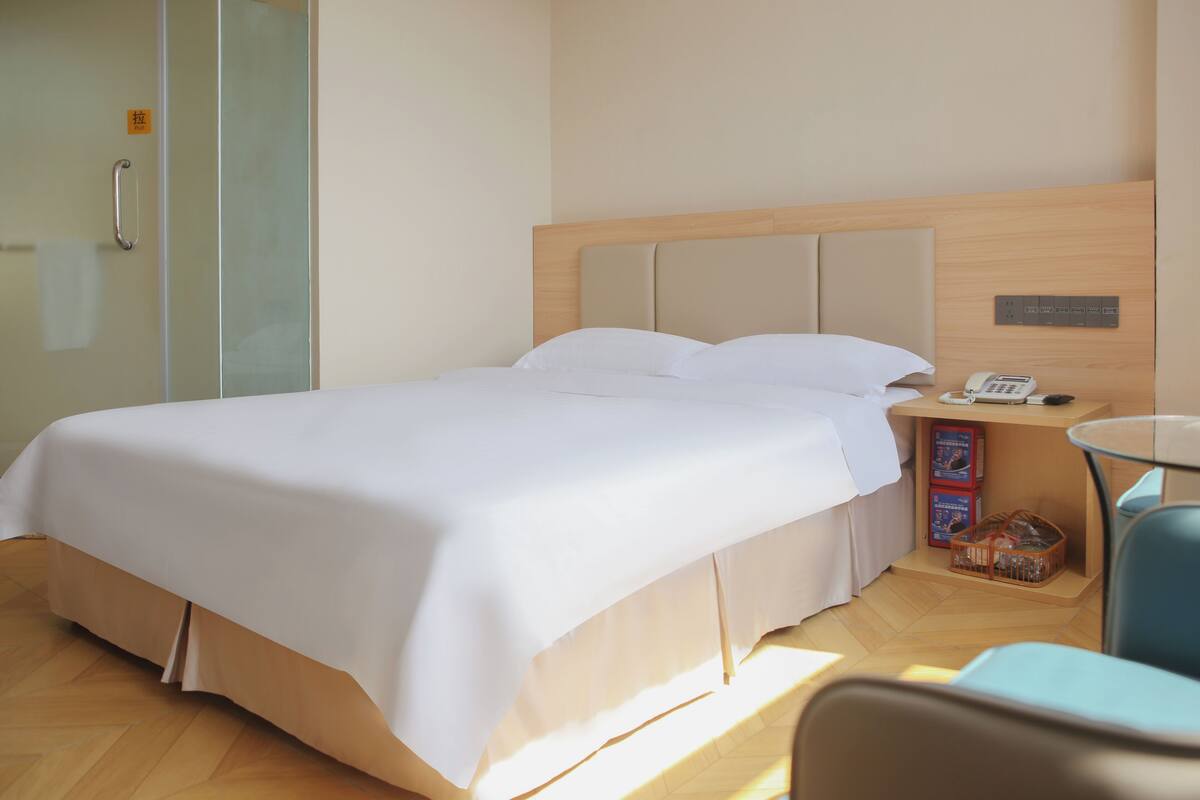 A hotel room with a bed, bedside table, and a chair.