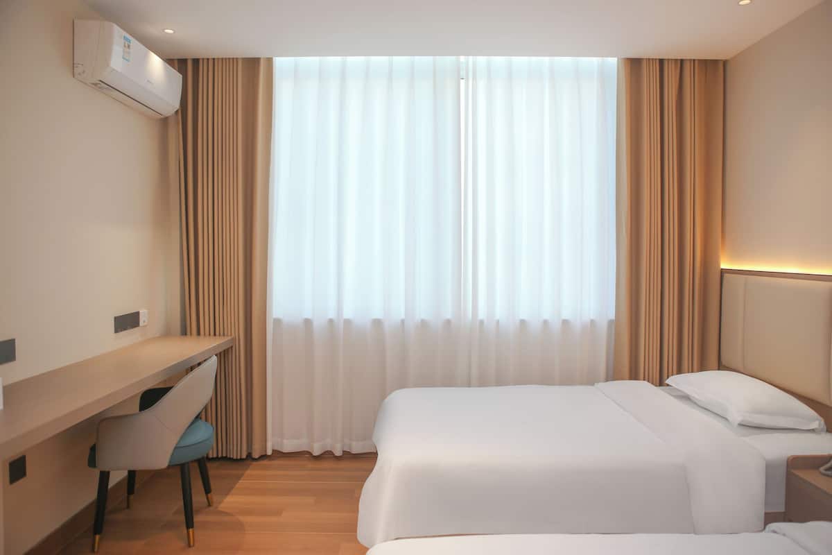 A hotel room with a bed, a desk, and a chair.