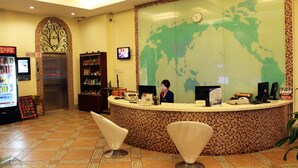 A reception area with a tiled wall, a clock, a television, and a vending machine. - Green Oasis Hotel (Shenzhen)