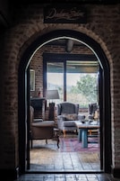 Uma porta arqueada dá acesso a uma área de estar aconchegante, com lareira, mesa e vista para o exterior.